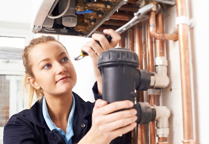 Highwaystarz-Photography female-plumber-working-on-central-heating-boiler-picture-id522776150